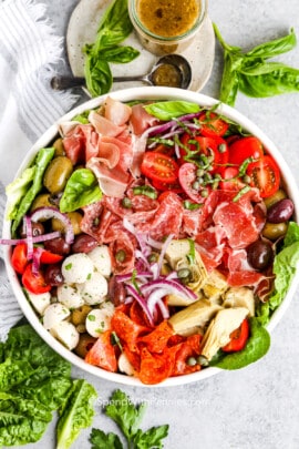 antipasto salad in a while bowl with dressing on the side