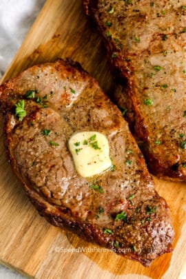 cooked air fryer steaks on a wood board with butter