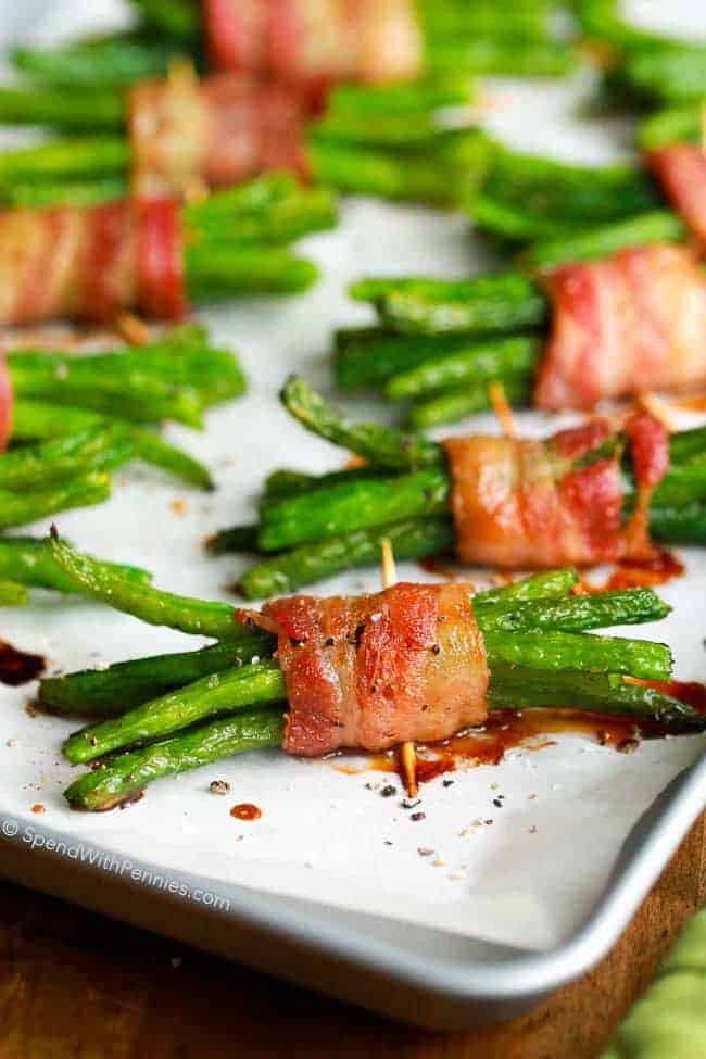 bacon wrapped green bean bundles on a baking tray with toothpicks holding them together