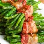 a stack of bacon wrapped green bean bundles on a white plate
