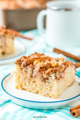 Slice of cinnamon coffee cake on a small dessert plate on a blue and white napkin.