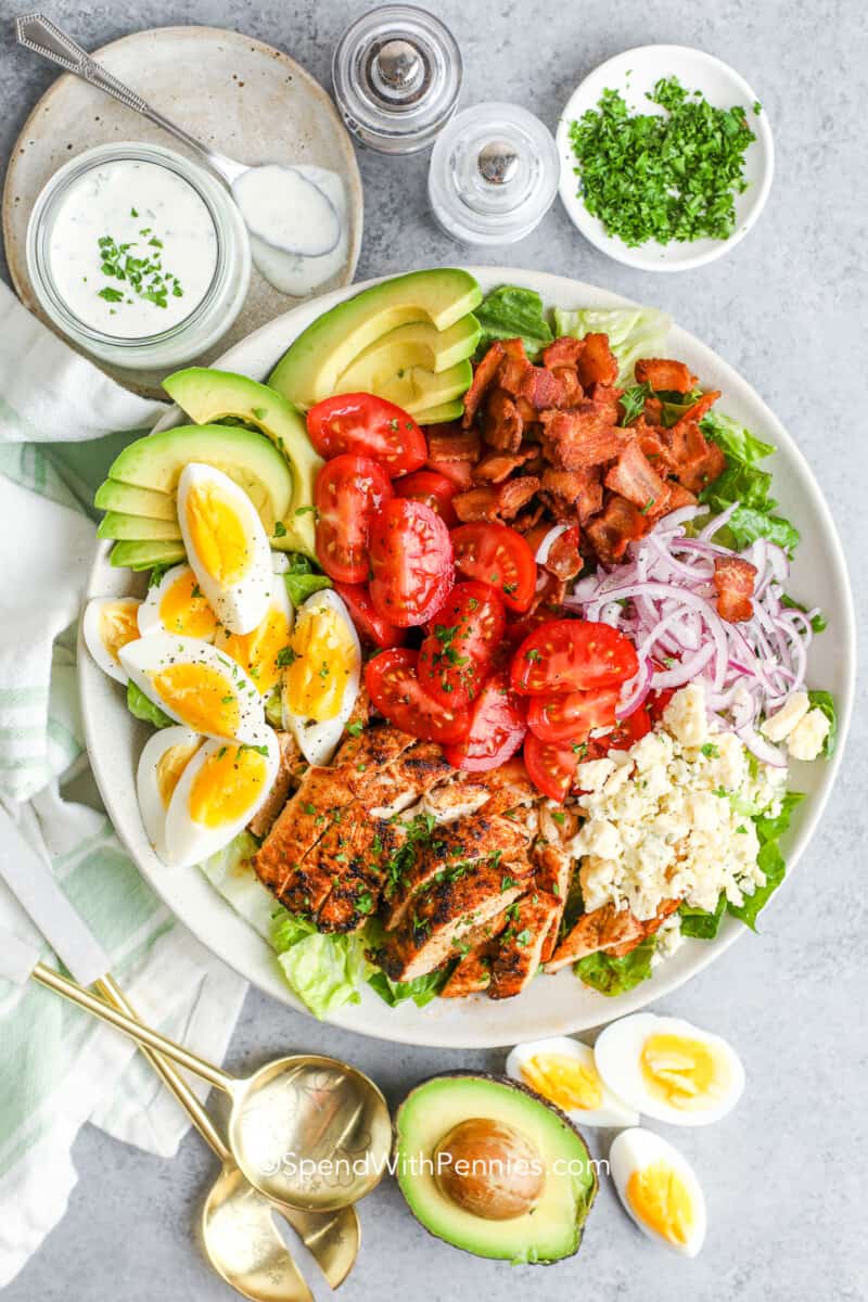 cobb salad on a plate with a creamy dressing next to it