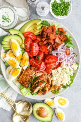 a prepared cobb salad in a salad bowl with creamy dressing, eggs and avocados