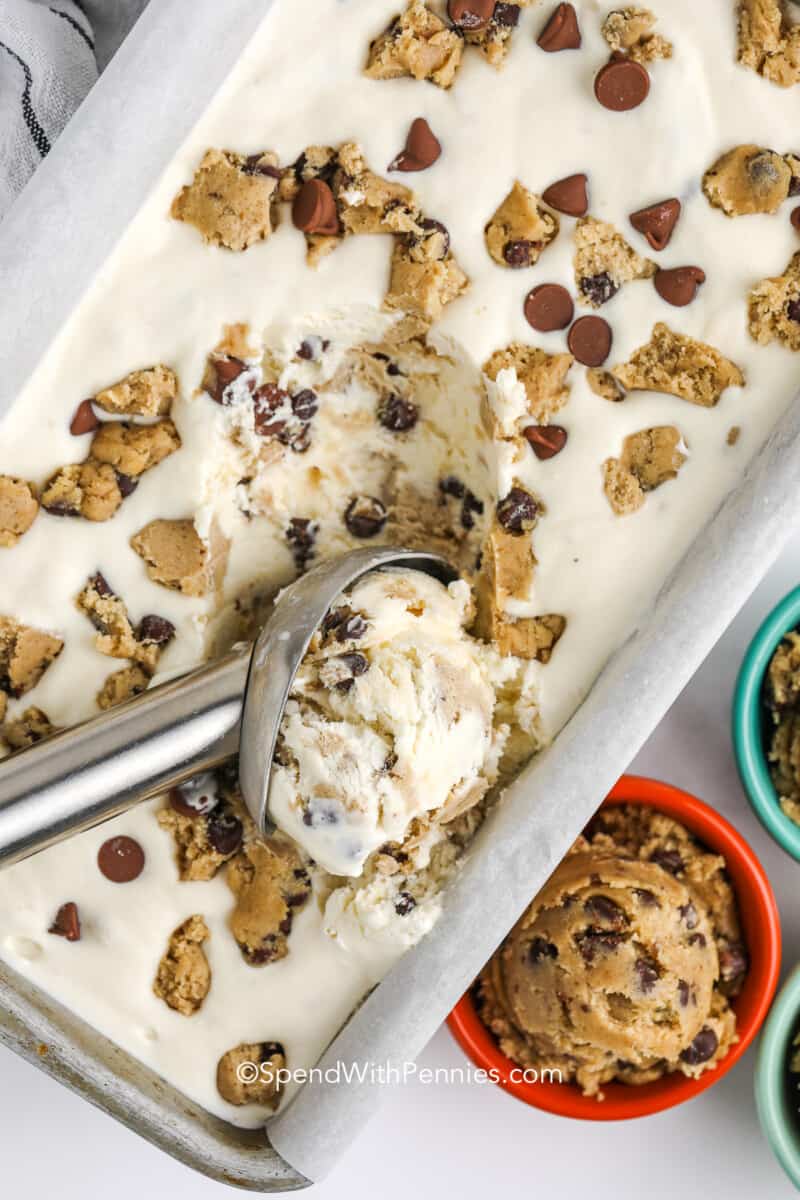 an ice cream scoop scooping a loaf pan with cookie dough ice cream inside