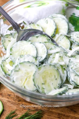 Creamy Cucumber Salad in a mixing bowl being stirred with a spoon