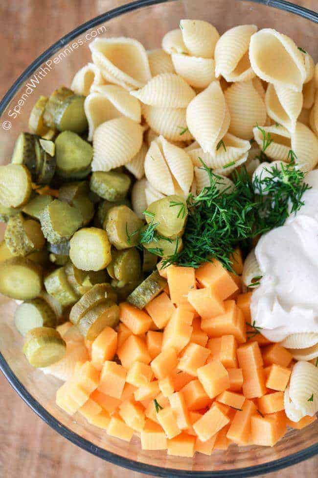 Dill PIckle Pasta Salad ingredients in a clear glass bowl before mixing together