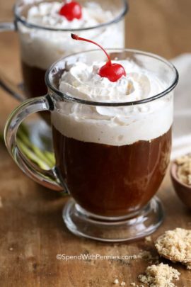 Irish coffee in a clear mug topped with whipped cream and cherry