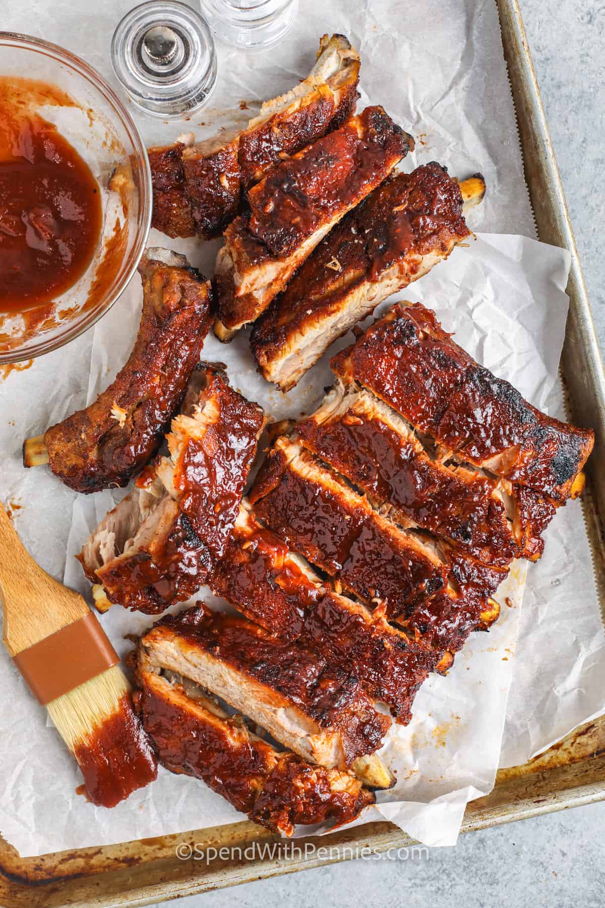 cut Oven Baked Ribs on a sheet pan with sauce