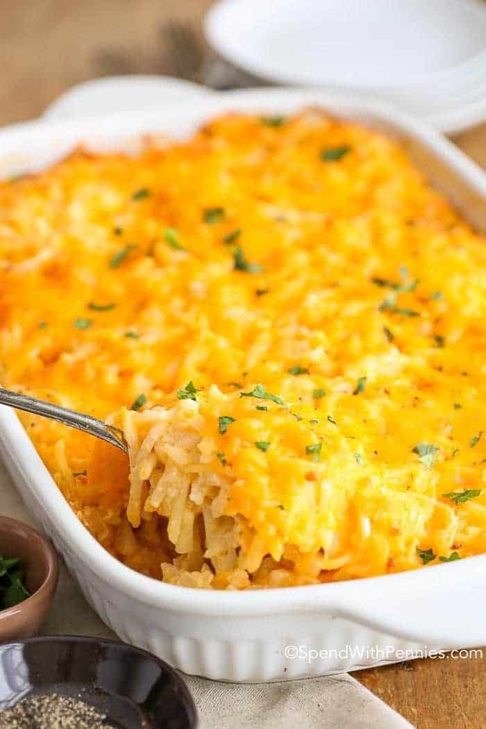 Serving spoon of Hashbrown Casserole in a casserole dish 