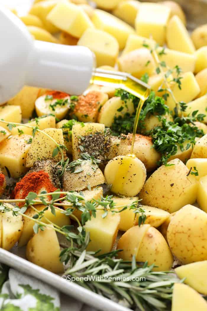 Adding fresh herbs, spices and olive oil to potatoes for the perfect oven roasted potatoes recipe