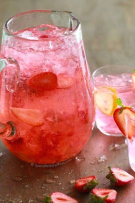 Big clear jar of Homemade Strawberry Lemonade with a glass of it next to it