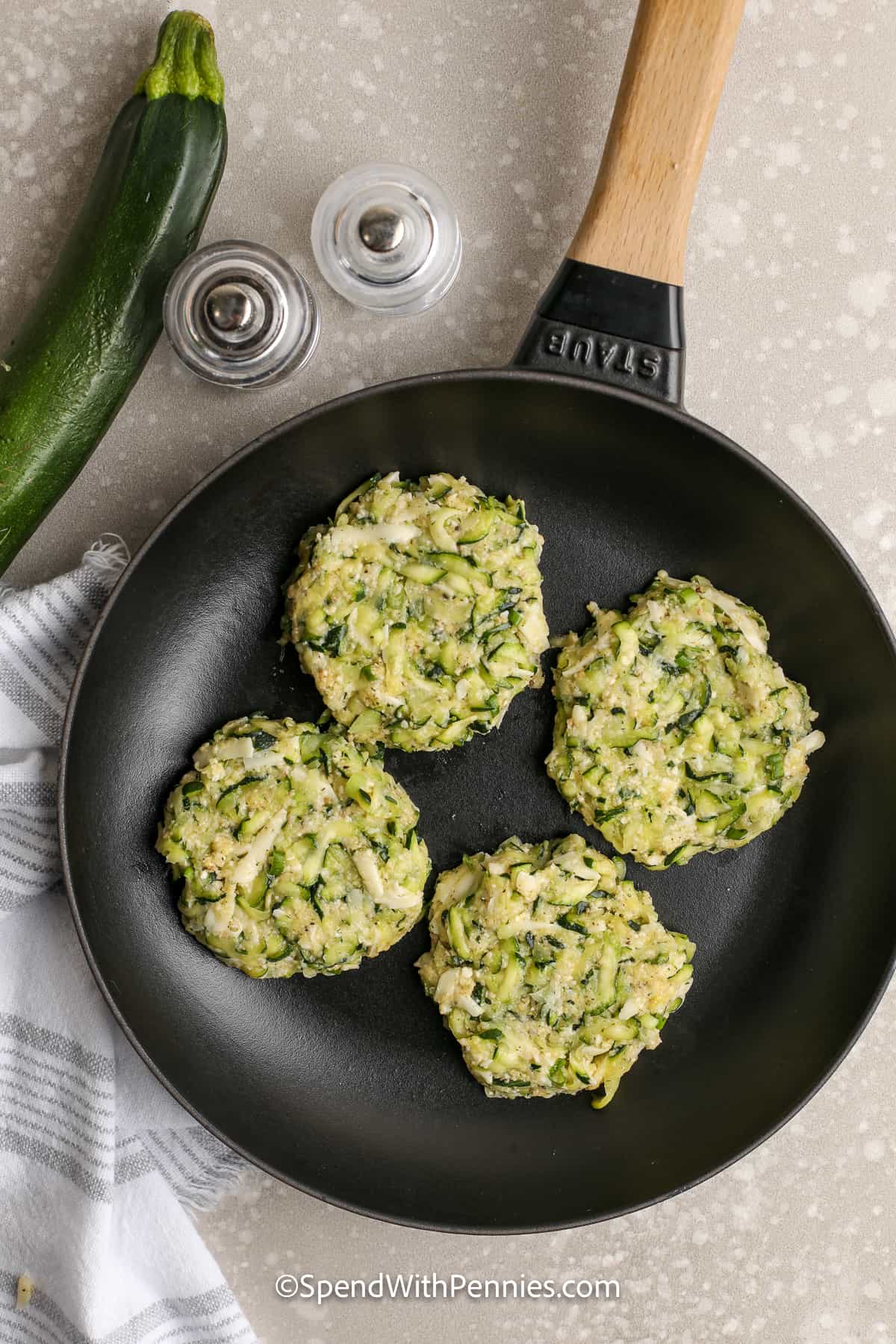uncooked zucchini fritter patties in a skillet