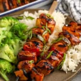 teriyaki chicken kabobs on a bed of rice with steamed broccoli